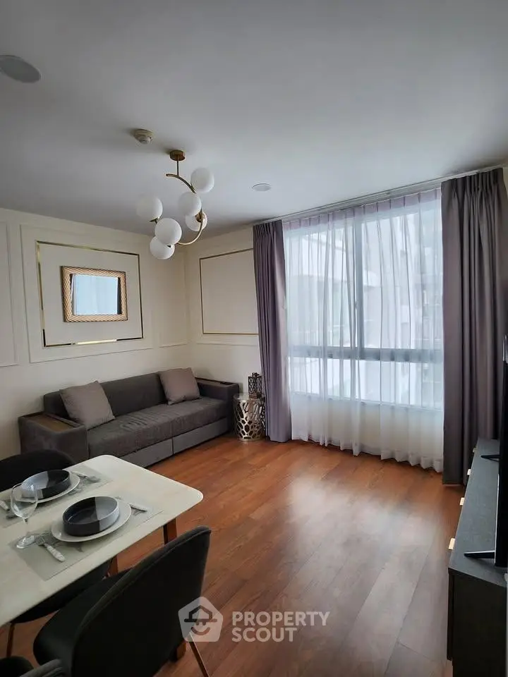Modern living room with elegant decor and large window, featuring a cozy sofa and dining area.
