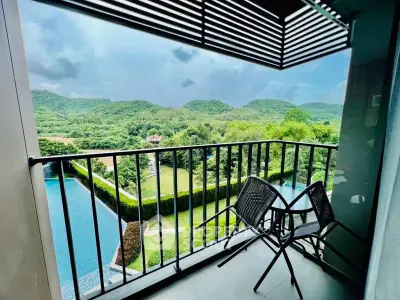 Stunning balcony view overlooking lush green hills and serene pool area.