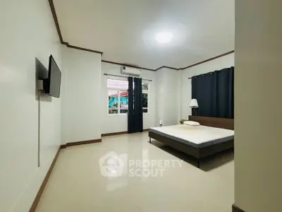Spacious bedroom with modern decor and large window for natural light.