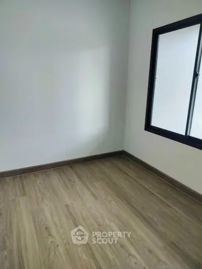 Spacious empty room with wooden flooring and large window