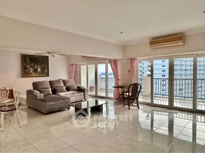 Spacious living room with large windows and balcony offering stunning city views.