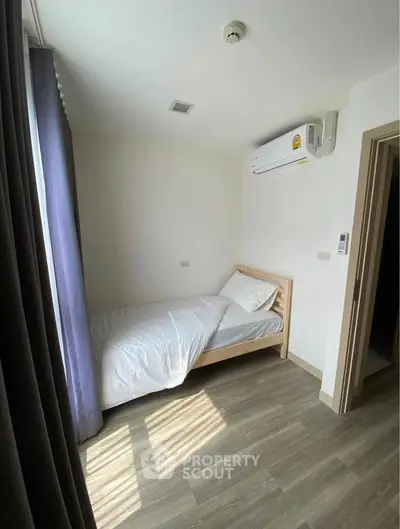 Cozy minimalist bedroom with natural light and modern air conditioning unit.