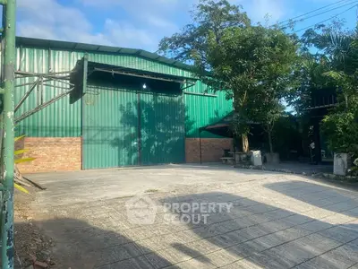 Spacious industrial warehouse with large green doors and ample outdoor space.