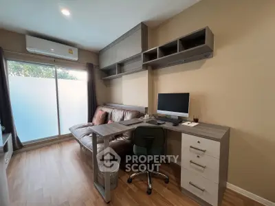Modern study room with desk, computer, and sofa in a cozy apartment setting.