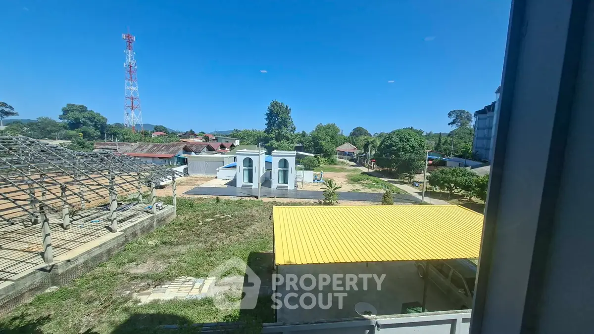Scenic view from window overlooking lush greenery and distant buildings, perfect for serene living.