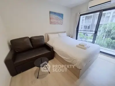 Cozy bedroom with modern decor, featuring a comfortable bed, sofa, and large window with garden view.