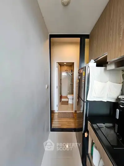 Modern kitchen with sleek appliances leading to a compact bathroom, showcasing efficient use of space.