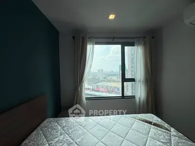 Cozy bedroom with city view, featuring a large window and elegant curtains.
