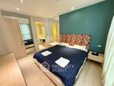 Spacious bedroom with floral headboard and modern decor in a well-lit apartment.