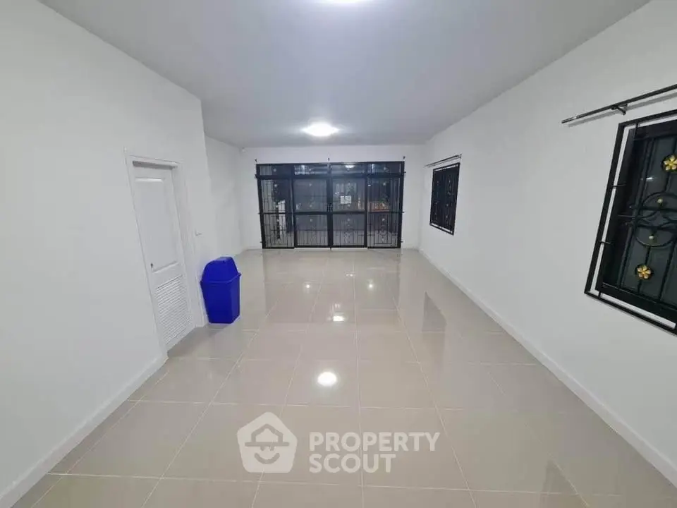 Spacious empty room with tiled floor and large windows, ideal for customization.