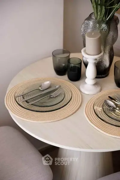 Elegant dining setup with glass plates and candles on a round table, perfect for cozy meals.