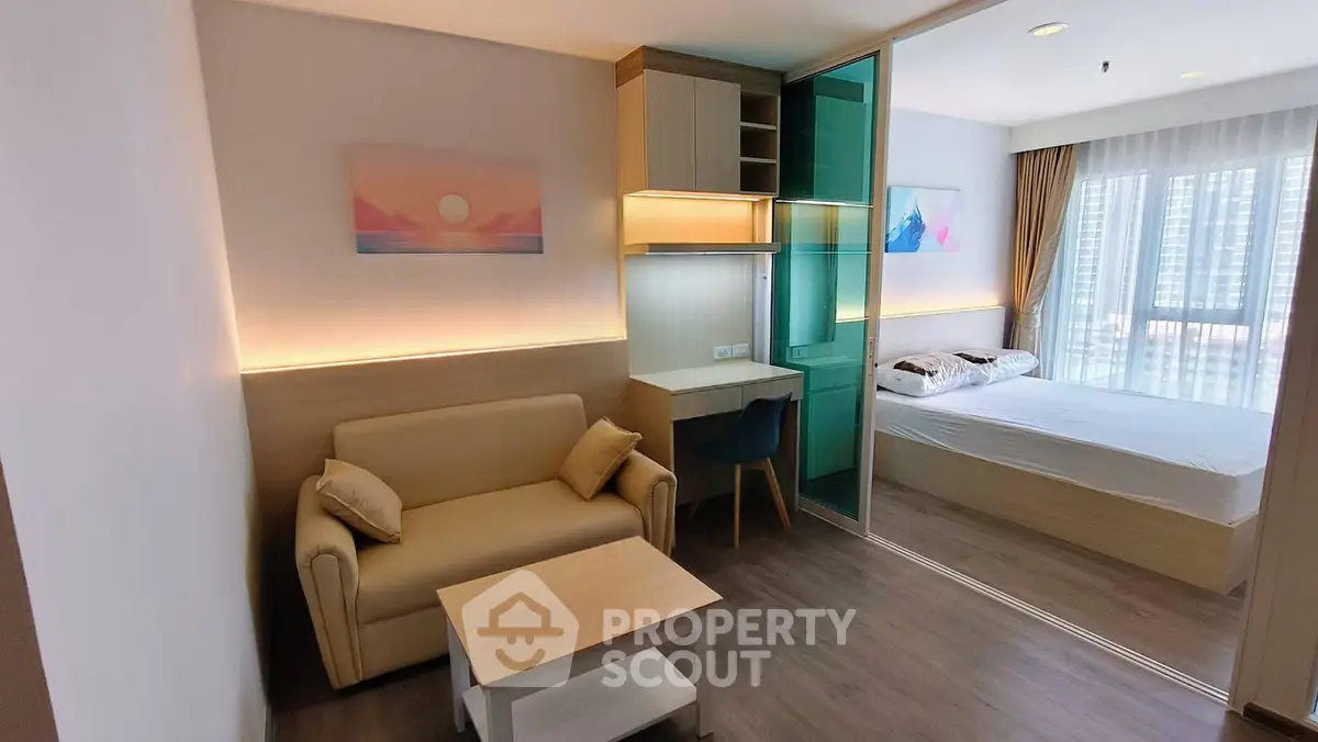 Modern studio apartment with cozy living area and bedroom separated by glass partition, featuring stylish decor.