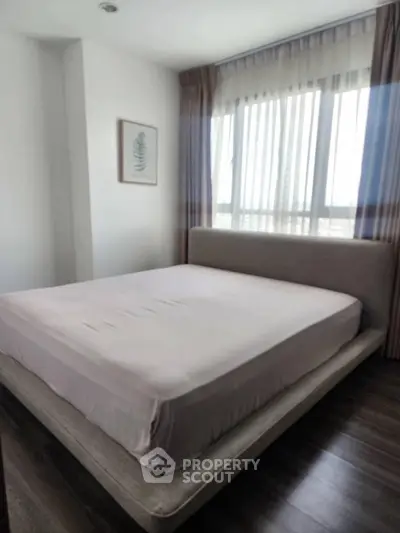 Spacious bedroom with large window and modern decor in a stylish apartment.