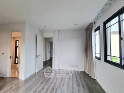 Spacious bedroom with modern flooring and large windows for natural light.