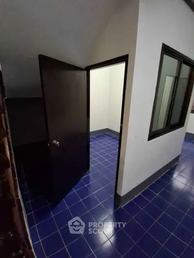 Compact room with blue tiled flooring and open door, ideal for storage or small office space.