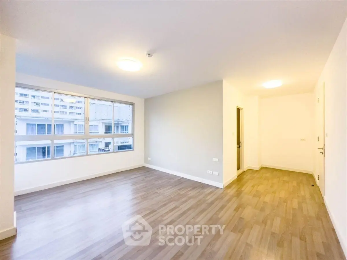 Spacious empty living room with large windows and wooden flooring