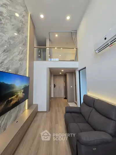 Modern living room with high ceiling and mezzanine, featuring sleek design and cozy ambiance.