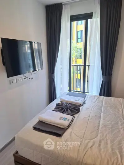 Modern bedroom with wall-mounted TV and balcony view