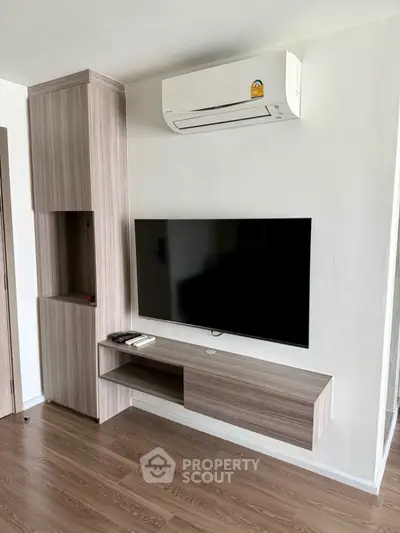 Modern living room with sleek TV unit and air conditioning, featuring stylish wood flooring and contemporary design.