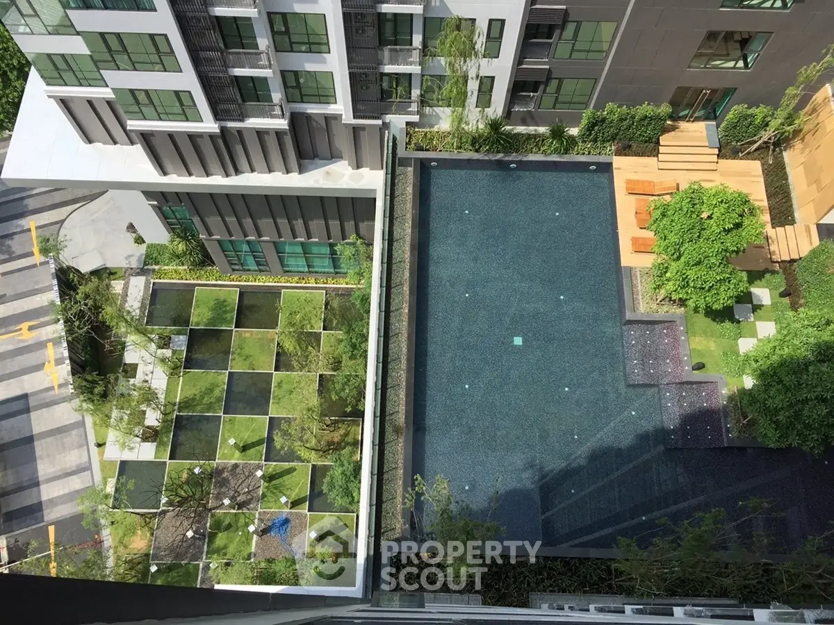 Modern apartment complex with rooftop pool and landscaped garden view from above.