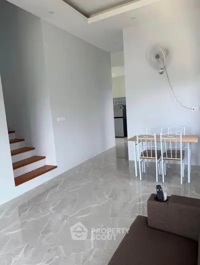 Modern interior with marble flooring, staircase, dining area, and sleek kitchen appliances.