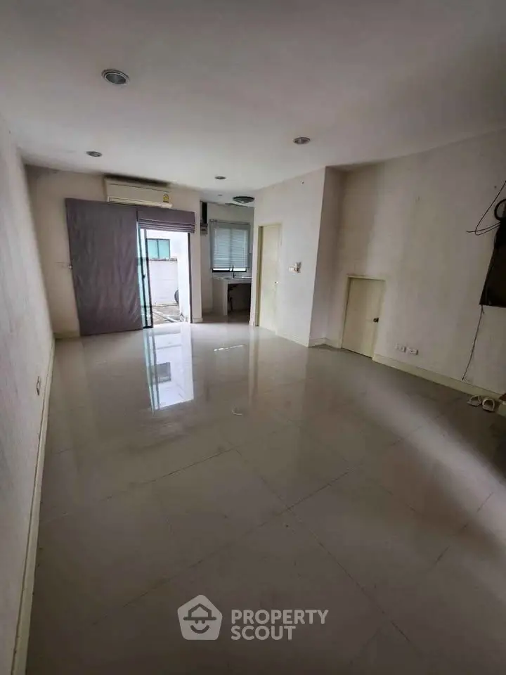 Spacious empty room with glossy tiled floor and natural light, ideal for customization.