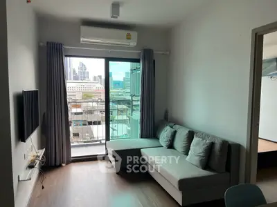 Modern living room with city view, featuring a sleek gray sofa and wall-mounted TV.