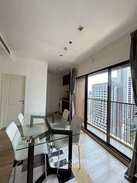 Modern dining area with city view and glass table in high-rise apartment.