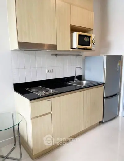 Modern kitchen with sleek cabinets, microwave, and fridge in compact layout.