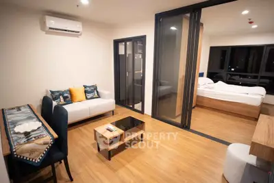 Modern open-layout living room with cozy bedroom, stylish furniture, and wooden flooring in a contemporary apartment.