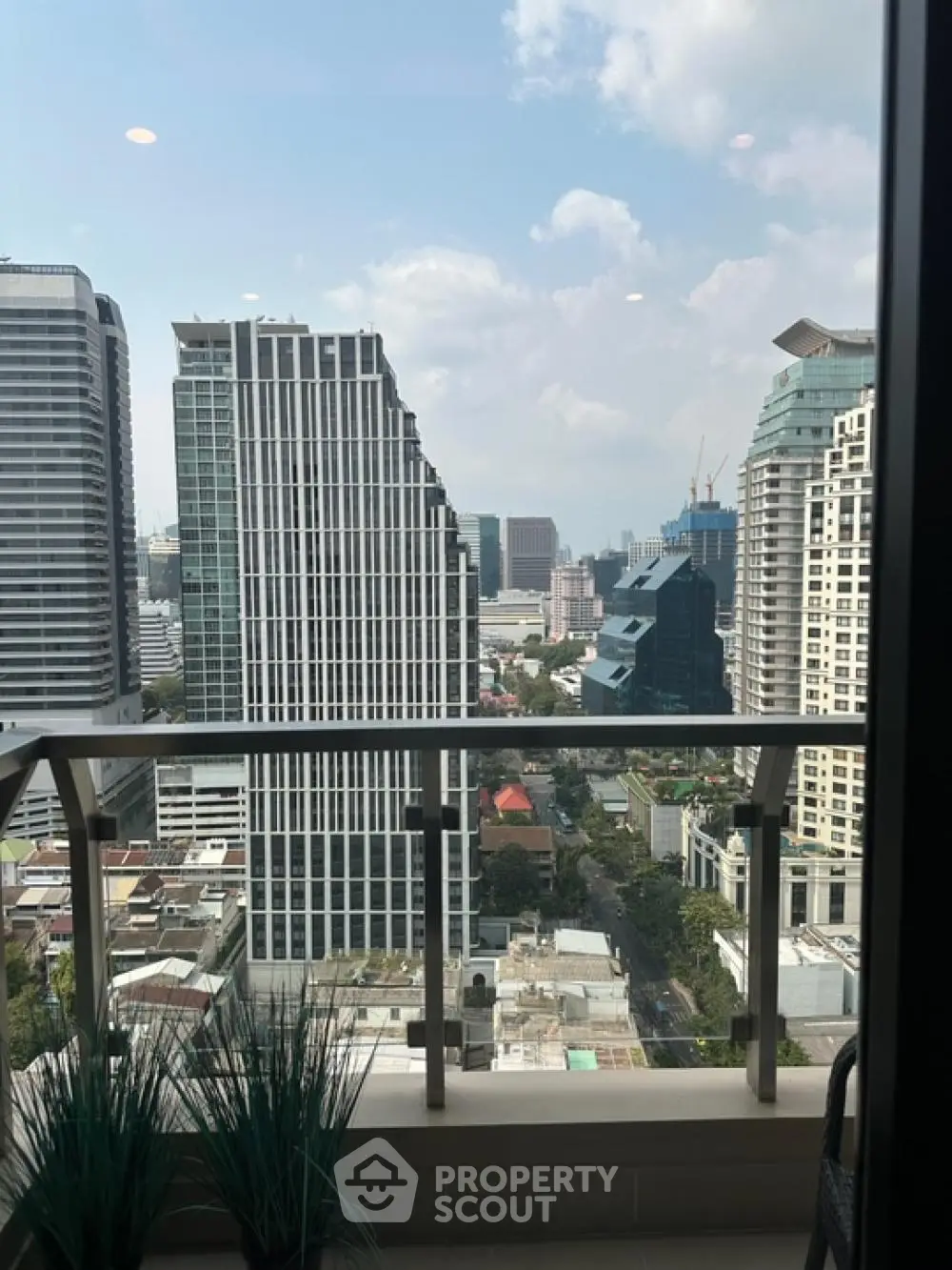Stunning city view from modern high-rise balcony with glass railing.