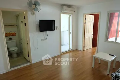 Spacious living room with modern amenities and wooden flooring, featuring a wall-mounted TV and air conditioning.