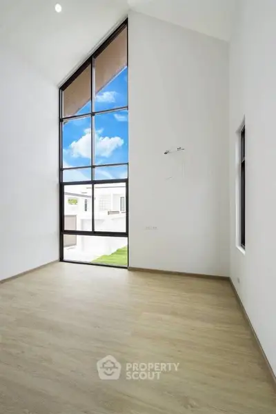 Spacious room with high ceilings and large windows offering a bright and airy atmosphere.