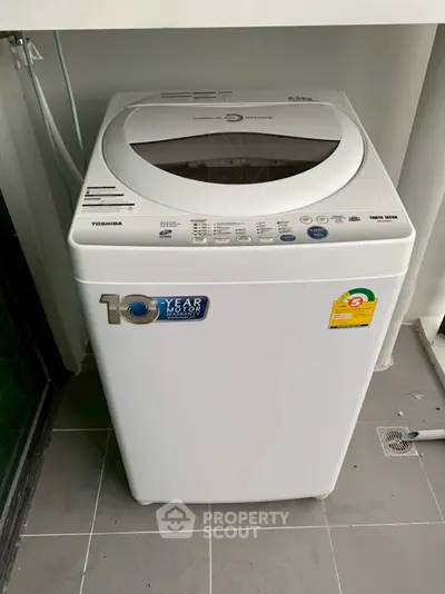 Modern washing machine on tiled balcony with energy efficiency label