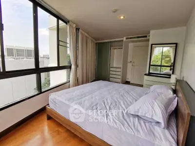 Spacious bedroom with large windows and modern furnishings in a high-rise apartment.