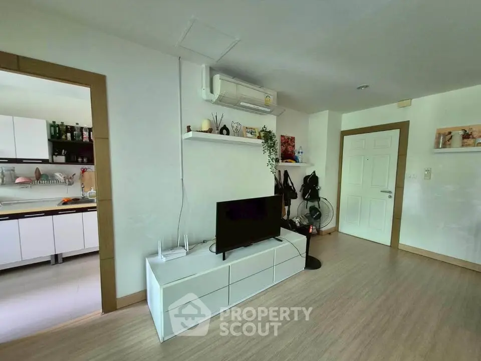 Modern living room with sleek white furniture and open kitchen layout