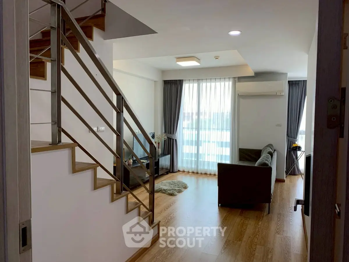 Modern duplex living room with sleek staircase and natural light