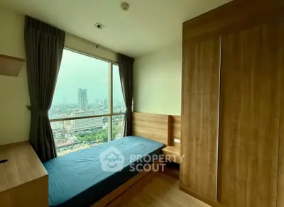 Cozy bedroom with city view, featuring wooden furniture and large window for natural light.