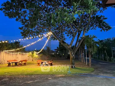 Charming outdoor garden with string lights and seating area at dusk, perfect for relaxation.