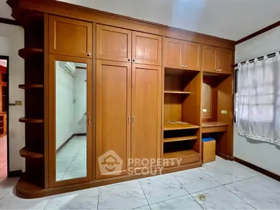 Spacious bedroom with built-in wooden wardrobe and tiled flooring