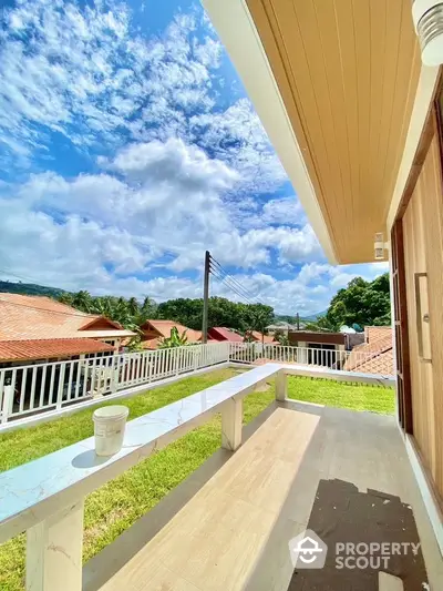 Stunning balcony view with lush greenery and clear blue sky in a serene neighborhood.