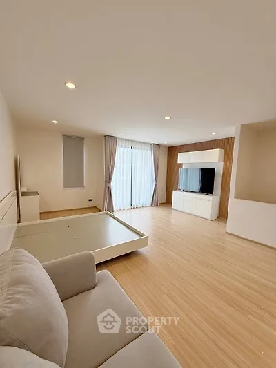 Spacious modern living room with wooden flooring and large windows for natural light.