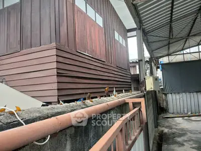 Traditional wooden house exterior with corrugated metal roofing and concrete fence
