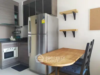 Modern kitchen with stainless steel fridge, wooden cabinets, and cozy dining area.