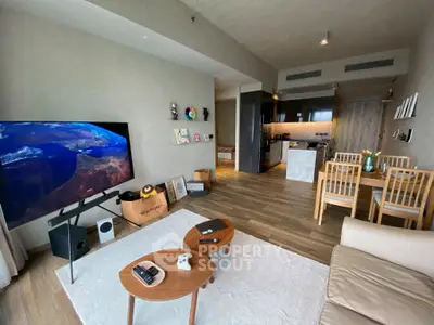 Modern living room with open kitchen, stylish decor, and large TV in a cozy apartment.