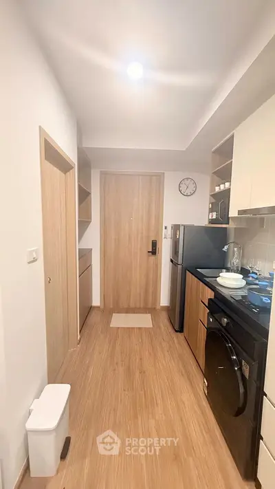 Modern kitchen with sleek appliances and wooden flooring in a cozy apartment.