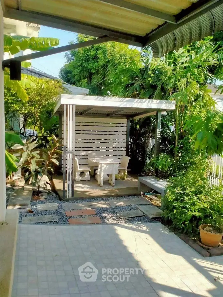 Charming garden patio with lush greenery and cozy seating area, perfect for outdoor relaxation.