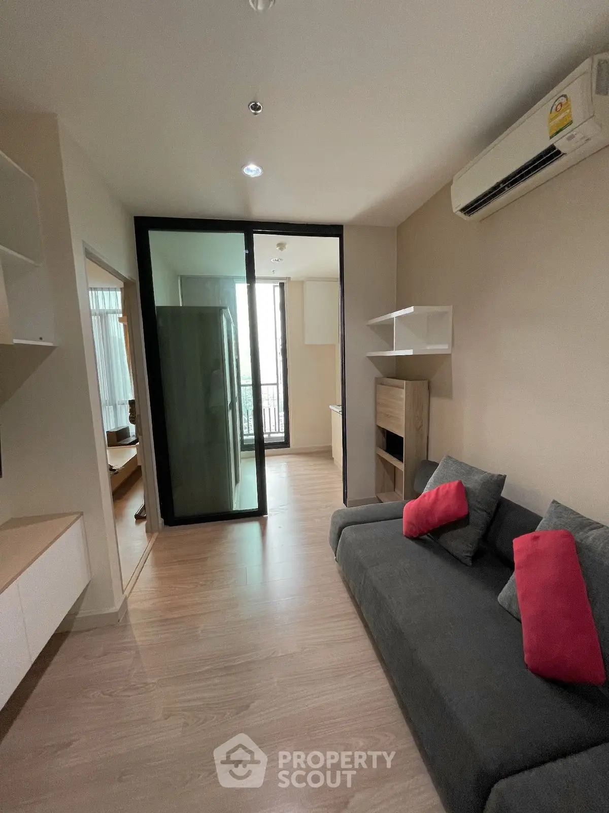 Modern living room with sleek design and air conditioning, featuring a cozy sofa and stylish shelving.