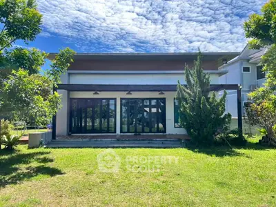 Modern house exterior with lush green lawn and clear blue sky, showcasing contemporary architecture.