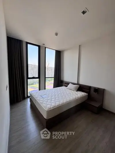 Modern bedroom with large windows and minimalist design in a stylish apartment.